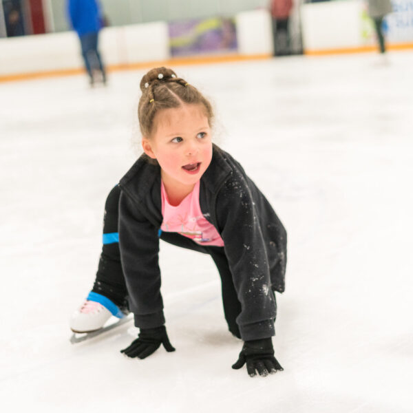 Young figure skater playing on indoor ice arena.